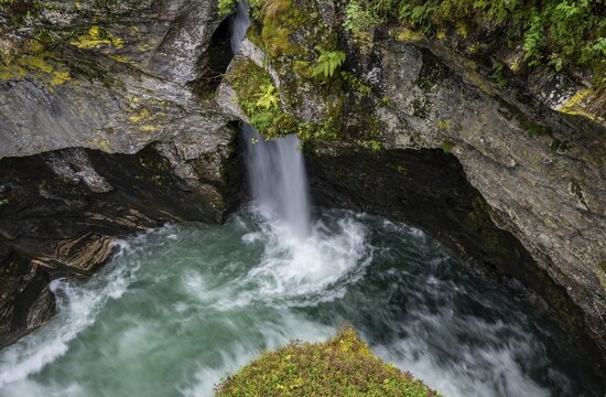 View of a small waterfall and a pool from the historic &Oslash;vstest&oslash;lbrua stone arch bridge, long exposure, Valldal, Norway