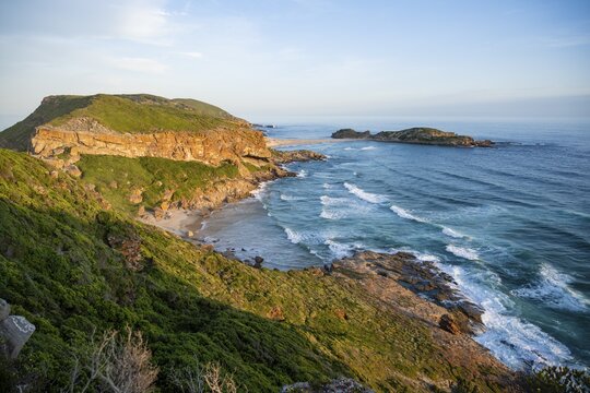 Young pretty woman wearing dress off coast and sea at Robberg Nature Reserve, Plettenberg Bay, South Africa