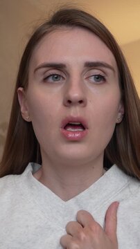 Young woman feeling weak and unwell at home, experiencing dizziness, fatigue, nausea and low energy while showing visible discomfort and exhaustion.