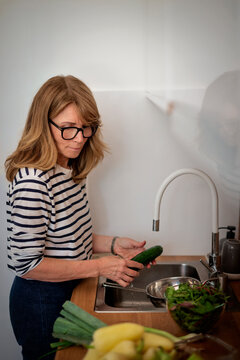 Blond haired middle-aged woman preparing vegetables in her modern kitchen
