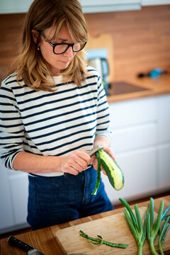 Blond haired middle-aged woman preparing vegetables in her modern kitchen