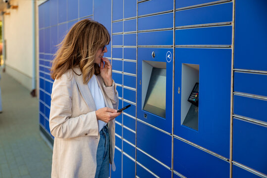 Thinking woman collecting her package in front of a parcel locker