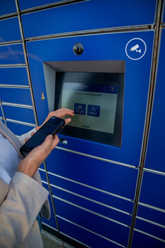 Close-up of a woman's hand touching the parcel locker touch screen