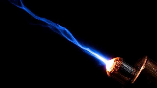 Molten electrode tip glowing white hot with blue flame and sparks emitting intense energy effect in dark background welding torch scene