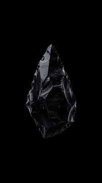 Ancient Obsidian Arrowhead Tool on a Black Background