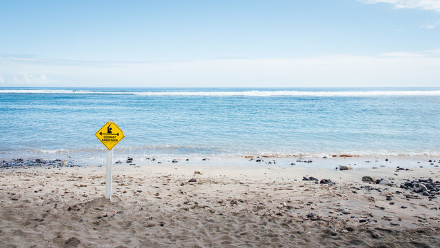 Paysage d'une plage &agrave; La R&eacute;union avec un panneau jaune d'avertissement des risques de noyade. Attention aux courants dangereux dans la mer. Dangers de la mer.
