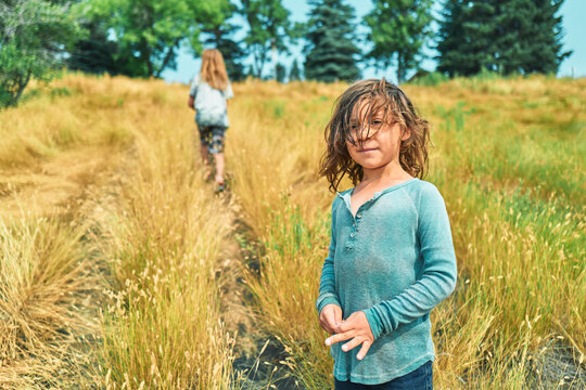 Two boys on a hillside path through tall golden grass