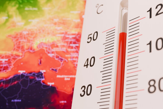 Close-up of a thermometer displaying a scorching 40&deg;C on a fiery global heat map of Europe and the Mediterranean, illustrating extreme heat waves and climate change.