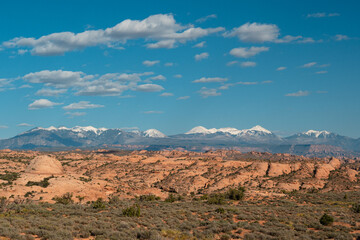 Naklejka premium Layers of clouds, snowy mountains, and desert rock formations in Utah