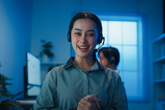 Gen z Asia young call center team or customer support service executive use computer and microphone headset work technical e commerce support in late night office. Telemarketing or sales job concept.