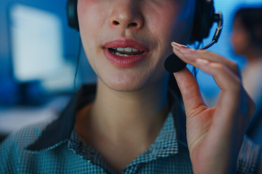 Closeup Gen z Asia young call center team or customer support service executive use computer and microphone headset work technical e commerce in late night office. Telemarketing or sales job concept.