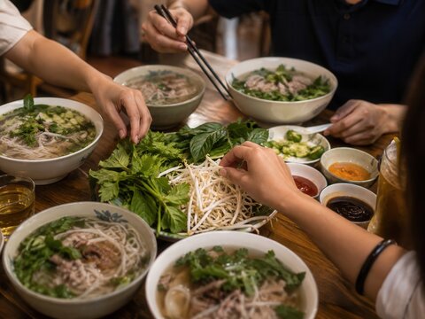 Gemeinsames Essen mit Pho am Tisch &ndash; Mehrere Sch&uuml;sseln vietnamesischer Nudelsuppe mit frischen Kr&auml;utern und Beilagen, eine authentische Szene f&uuml;r Familie, Freunde und Genussmomente.