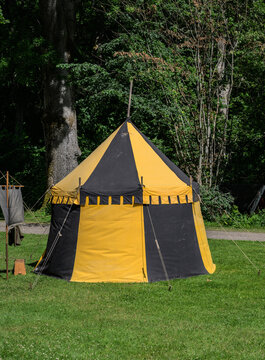 Black and yellow medieval style tent standing on green summer lawn.
