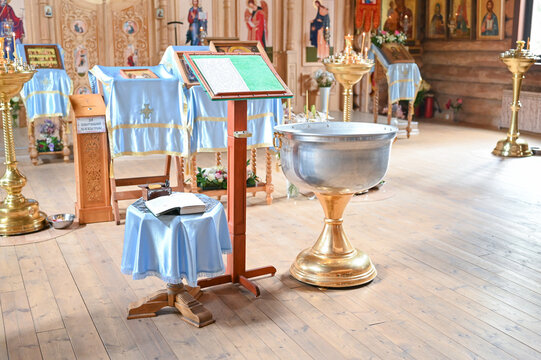 Silver baptismal font, lectern, iconostasis inside a traditional wooden Orthodox church prepared for a baptism ceremony. Good for religious articles, cultural publications, baptism concepts