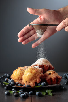Freshly baked blueberry muffins are dusted with icing sugar.