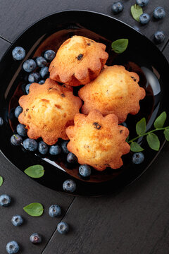 Freshly baked blueberry muffins on a black plate.