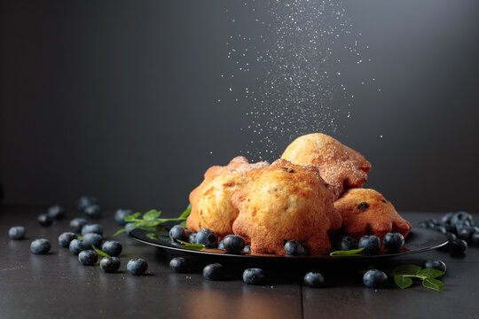 Freshly baked blueberry muffins are dusted with icing sugar.