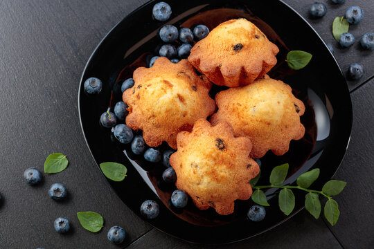 Freshly baked blueberry muffins on a black plate.