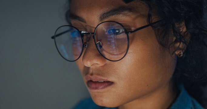 Close-up Black female programmer with code reflection in glasses working late in home office at night. Cybersecurity, AI algorithm, Network security, software developer, serious face, burnout concept.