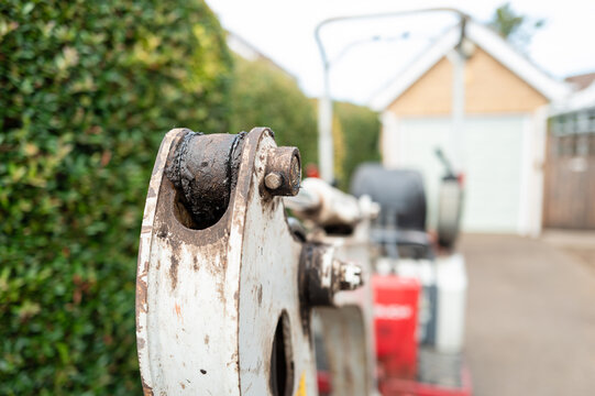 Shallow focus of the pivot joint of a small mechanical digger and excavator seen on a private driveway before being renovated. The driveway tarmac will soon be scooped up.
