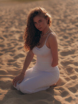 Amputee Woman Kneeling on Sand in Sunset
