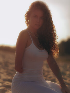 Amputee Woman Kneeling on Sand in Sunset