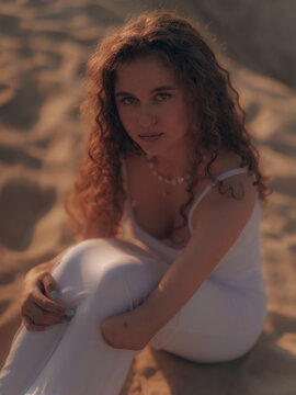 Amputee Woman Sitting on Sand Dunes Backlit by Sunset