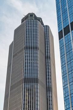 View of Tower 42, a prominent skyscraper in the City of London, featuring its distinctive vertical lines and glass facade against a bright sky in London, England, United Kingdom.