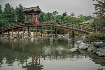 Fototapeta premium A beautiful young girl in a bright pink costume in a Japanese garden. The time of the year is summer.