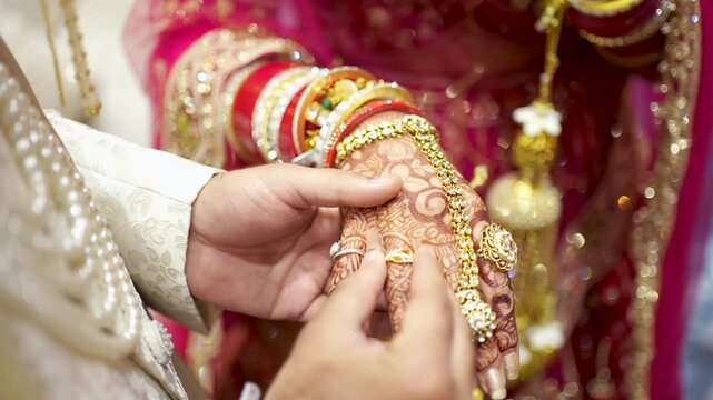 Groom putting wedding ring on bride hand during traditional Indian marriage ceremony