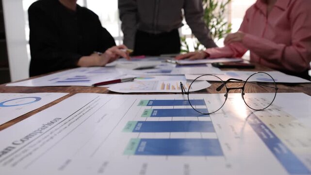 Business colleagues reviewing financial loan comparison reports. Group of business people analyzing financial documents and charts, brainstorming and discussing marketing strategy in the office.