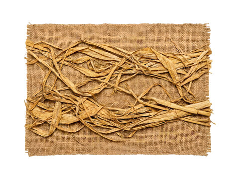 A rectangular piece of natural textured burlap fabric adorned with a complex, chaotic arrangement of dried raffia straw strands