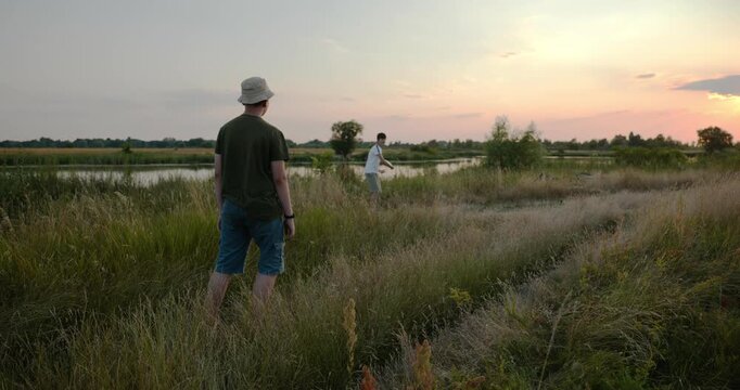 Two friends boys throw flying disk on nature. Teenagers spending time together. 4K 10-bit