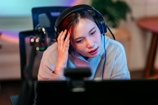 Professional streamer gamer playing video games online at home setup with neon lights focused on digital screen