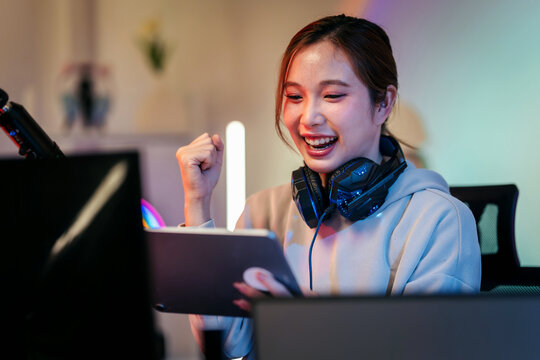 Empowered female gamer celebrates triumphant victory playing captivating online esports competition within vibrant modern home gaming studio