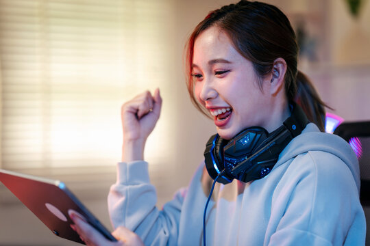 Excited young gamer achieves major success playing video games on tablet using her high tech headset at home