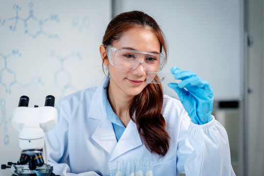 Professional scientist performs laboratory experiment holding medical sample for analysis discovery research expert wearing lab coat safety glasses at science facility