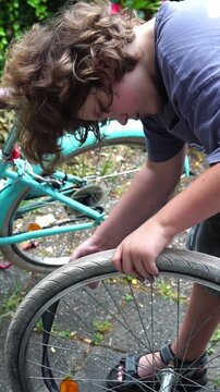 Teenage boy inserting inner tube into bicycle tire outdoors