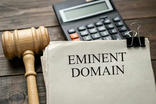 Eminent domain legal concept featuring a wooden gavel and a desk calculator property government acquisition courtroom business judicial regulations compensation ownership