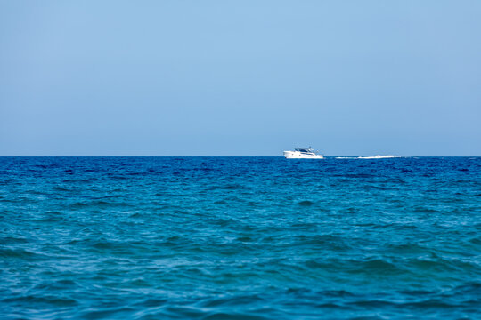 White yacht cruising on a calm blue ocean under clear sky, symbolizing travel, freedom, and summer leisure.