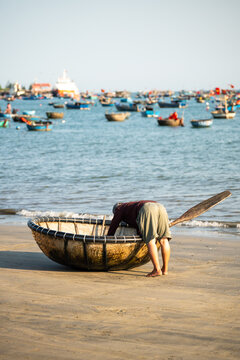 Unrecognizable fisherman on coast checking traditional Vietnamese round basket boat Thung chai, round bamboo fishing boat used by local fishermen to transport catch between shore and fishing vessels.