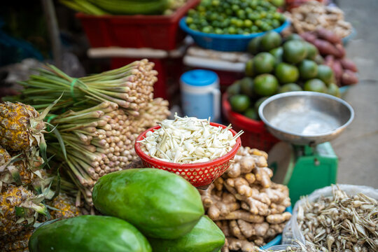 Vendor stall at street food market, fresh greens, fruits and vegetables wholesale at exotic marketplace, basins with garlic, lemongrass, ripe papaya, pineapples and ginger roots on sale for customers.