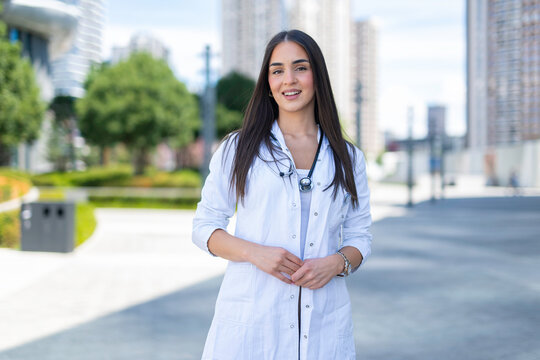 Female doctor smiling wearing lab coat in urban setting