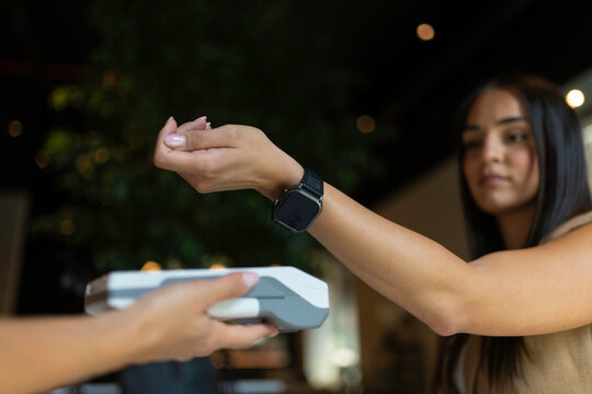 Young woman paying with a smartwatch over a payment terminal