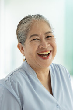 Happy joyful laughing old asian woman, female silver generation person with white hair showing positive friendly expressions, feeling good in home, indoors scene