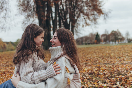 Loving mother and daughter sharing  tender moment together in autumn park. Mother's day, unconditional love, autumn lifestyle.