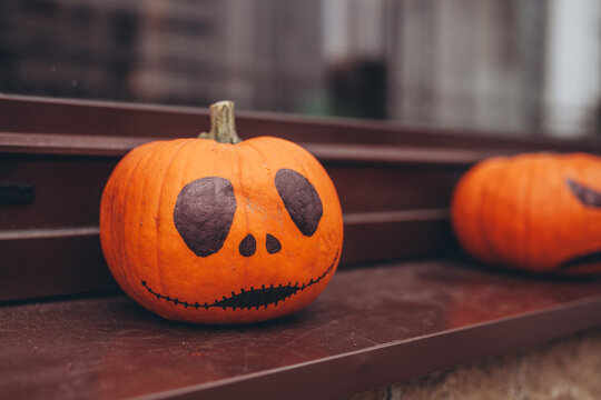 Hand-painted Halloween pumpkin with sitting on brown surface. Halloween and autumn decor. Festive mood.