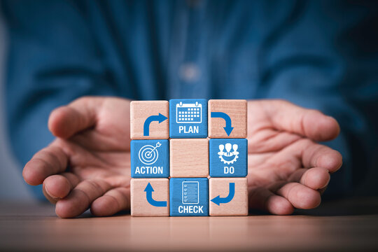 Hands giving wooden blocks with Plan Do Check Action cycle icons, symbolizing PDCA process, continuous improvement, quality management, business strategy, workflow, teamwork and productivity.