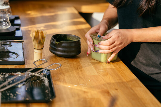 Close up of barista preparing green matcha drink with bamboo whisk in modern coffee shop