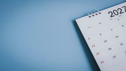 Close up of desk calendar year 2027 on blue background with copy space for planning concept.